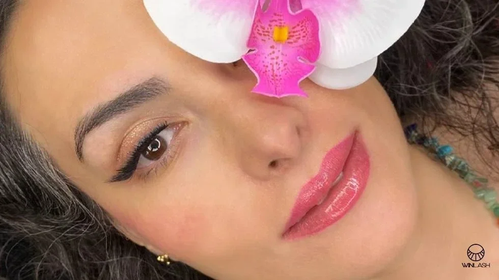 نمای نزدیک از چشم با مژه‌های کاشت موقت بلند و طبیعی همراه با گل‌ صورتی– کاشت موقت مژه وین‌لش